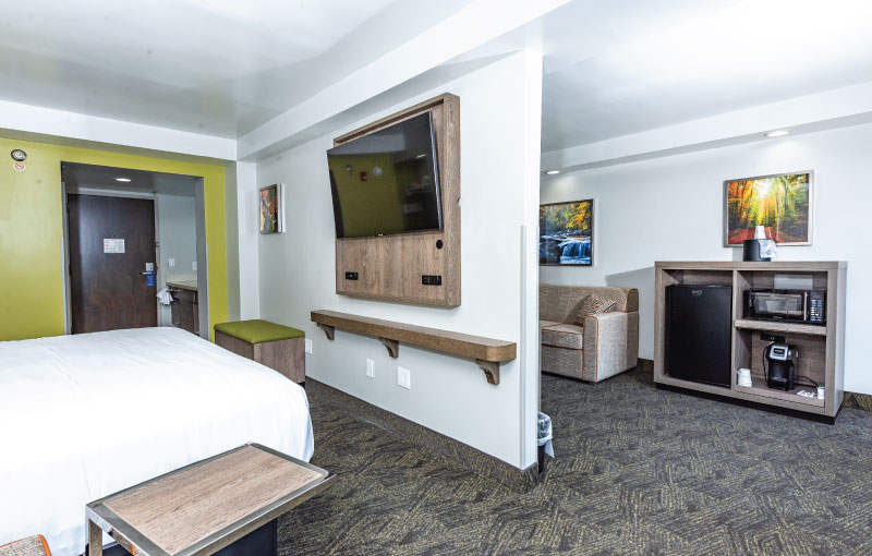 A suite with one king bed in one room and sofa, bunk bed in another room.